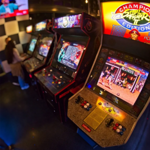 Rangée de bornes d’arcade rétro classiques avec écran Street Fighter II, ambiance de salle d’arcade des années 90, parfaite pour les passionnés de jeux vintage.